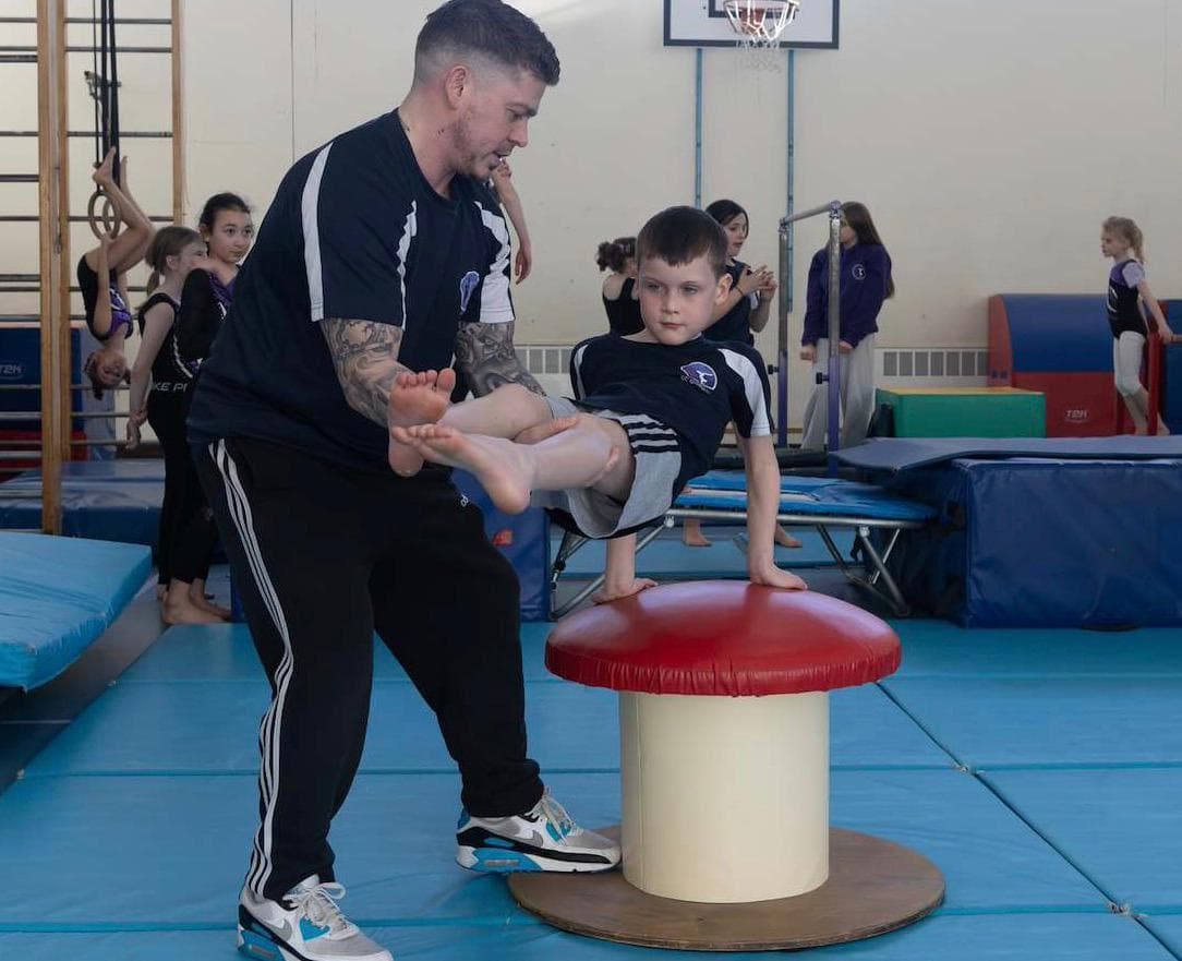 Gavin Chalmers coaching a gymnast in the gym