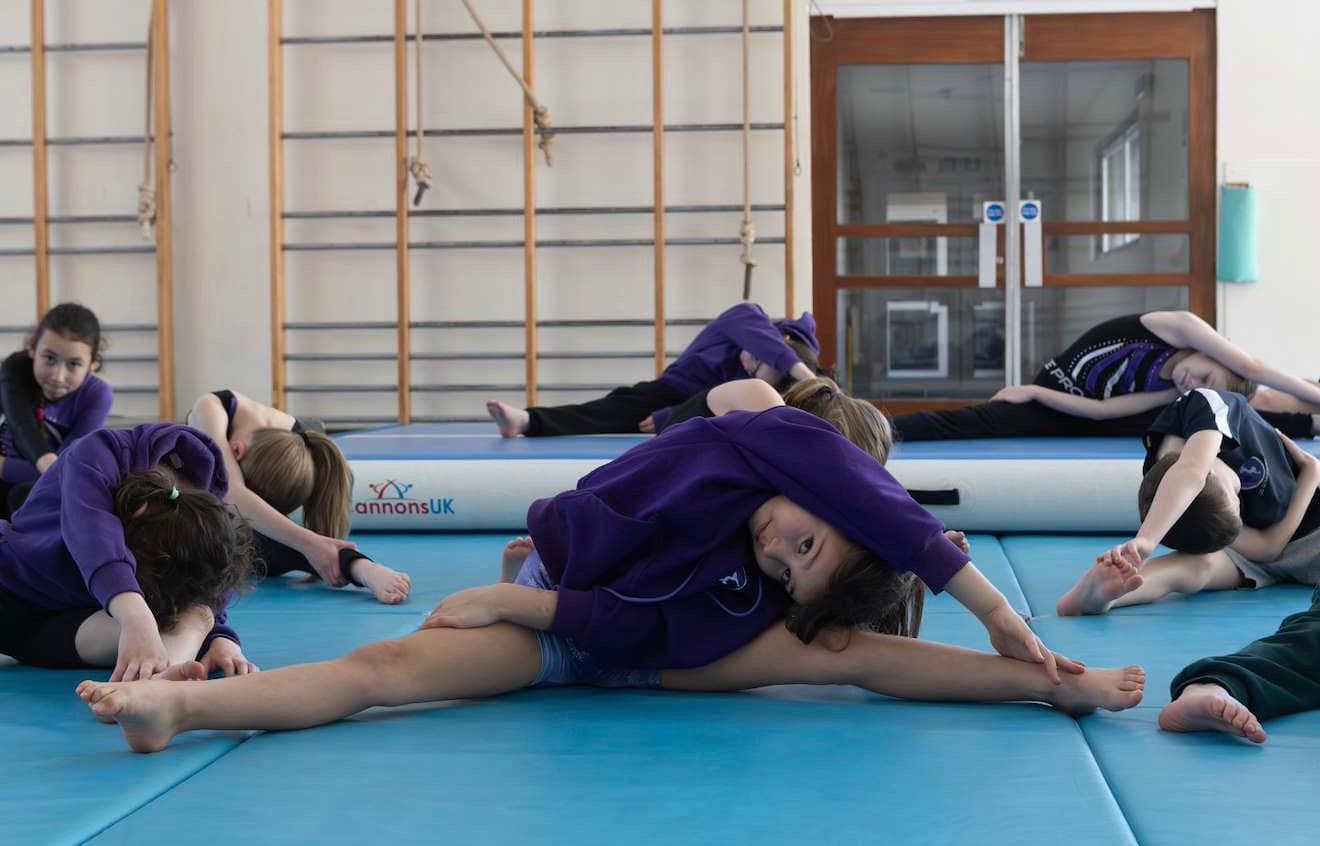 Children stretching on gymnastics mats in the gym hall